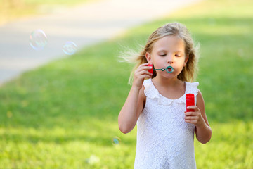 Cute girl blowing soap bubbles