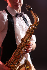 Fototapeta na wymiar Saxophone in female hands on dark background, close up