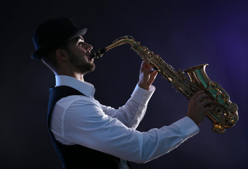 Obraz na płótnie Canvas Elegant saxophonist plays jazz on dark background