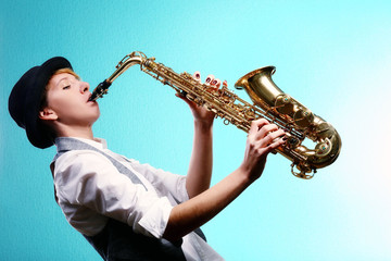 Fototapeta na wymiar Pretty woman plays music on saxophone in front of blue background