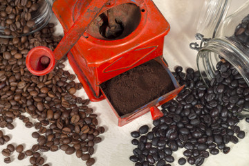 Top view of traditional manual coffee grinder beside different types of coffee beans