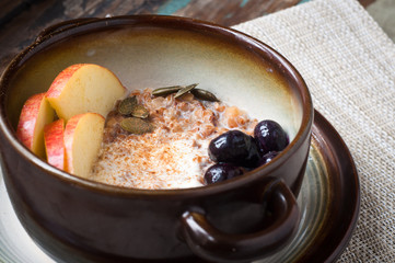 Healthy autumn, fall breakfast porridge of buckwheat groats topped with fresh sliced apple, blueberries,pumpkin seeds, chia seeds and walnuts.