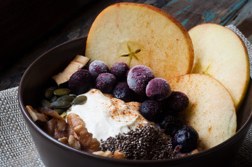 Healthy autumn, fall breakfast porridge of buckwheat groats topped with fresh sliced apple, blueberries,pumpkin seeds, chia seeds and walnuts.