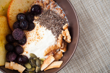 Healthy autumn, fall breakfast porridge of buckwheat groats topped with fresh sliced apple, blueberries,pumpkin seeds, chia seeds and walnuts.