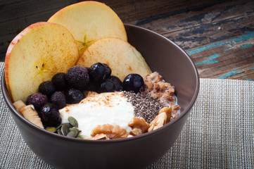 Healthy autumn, fall breakfast porridge of buckwheat groats topped with fresh sliced apple, blueberries,pumpkin seeds, chia seeds and walnuts.