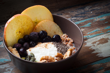 Healthy autumn, fall breakfast porridge of buckwheat groats topped with fresh sliced apple, blueberries,pumpkin seeds, chia seeds and walnuts.