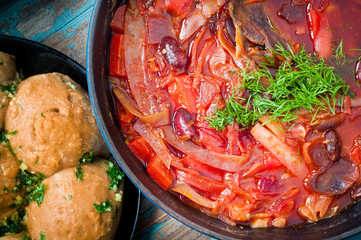 Traditional Ukrainian beetroot broth, known as Borshch, served with Pampushky garlic bread on a rustic wooden table. A delicious vegetarian dish common in Eastern Europe.