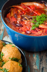 Traditional Ukrainian beetroot broth, known as Borshch, served with Pampushky garlic bread on a rustic wooden table. A delicious vegetarian dish common in Eastern Europe.