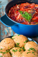 Traditional Ukrainian beetroot broth, known as Borshch, served with Pampushky garlic bread on a rustic wooden table. A delicious vegetarian dish common in Eastern Europe.