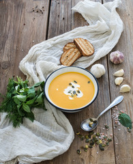 Pumpkin soup with cream, seeds, bread and fresh basil in metal