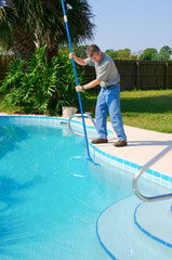 Residential pool cleaning service man working on a sparkling clean pool brushing the side clean - 94118816