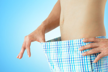 Young man looking inside his boxer shorts - sexual problem concept