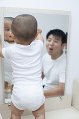 Chinese father and son playing in front of mirror