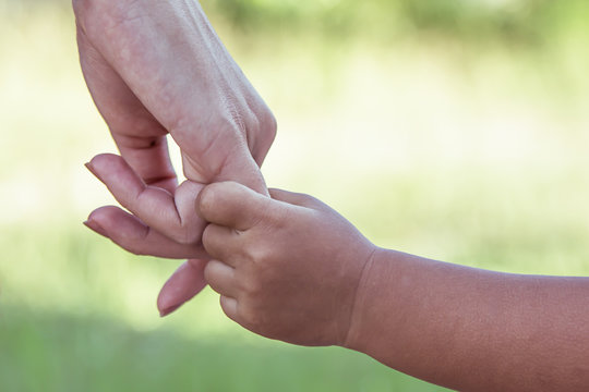 child and mother holding hand together with love in the park