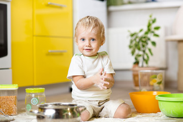 Little boy playing with kitchenware and foodstuffs in kitchen