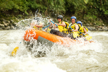 A team of adventurers navigate through white rapids on a raft, splashing through the rushing water of a wild whitewater river. - obrazy, fototapety, plakaty