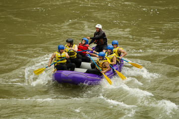 Experience the thrill of whitewater river rafting in Ecuador with a professional pilot guiding a diverse group of men and women tourists.