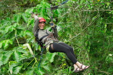 A woman gliding through the lush jungle canopy on a zipline in Baños, Ecuador, with the wind in her hair and excitement in her eyes.