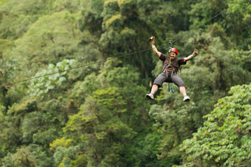 A group of people zip lining through the lush canopy of an Ecuadorian rainforest, surrounded by...