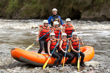 A young, adventurous team navigating through raging whitewater rapids on a rafting expedition down a wild river.