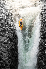 A thrilling image of kayakers navigating through dangerous white water rapids near a stunning waterfall, showcasing their courage and love for extreme sports.