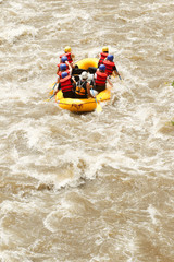 A diverse group of male and female tourists accompanied by an experienced guide navigating through turbulent whitewater rapids on a river rafting adventure in Ecuador