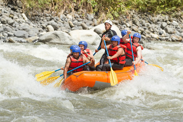 Fototapeta na wymiar A team of adrenaline junkies navigates through the white waters of an Ecuadorian river on a thrilling rafting expedition, laughing and rowing with determination.
