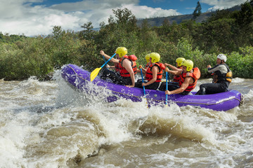 A team of men and women wearing helmets conquer the thrilling white rapids of an Ecuadorian river, united in their adventurous rafting competition.