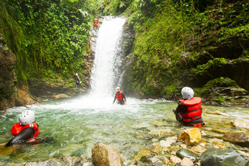 A family enjoying an action-packed outdoor adventure in Ecuador, rappelling down a waterfall, ziplining through the lush Llanganates forest and canyoning in the wet terrain. - obrazy, fototapety, plakaty