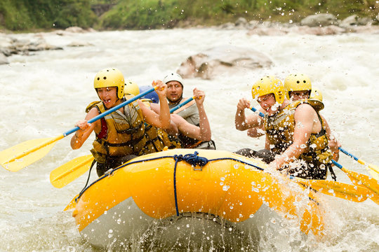 A group of adrenaline-seeking men rowing white rafts through extreme whitewater rapids, enjoying an outdoor team sport activity.
