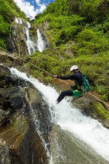 A thrilling rappel descent down a canyon in Ecuador, with the sound of a waterfall echoing through the lush green surroundings.