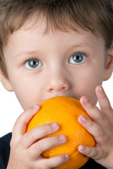 Young children proudly showing off his big orange pumpkin for Halloween.