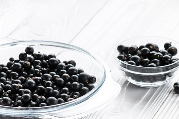 black currant in glassware on white wooden table