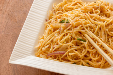 noodles on white bowl on top of wooden table 
