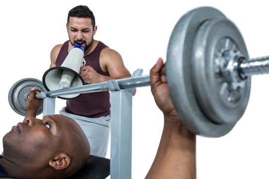 Trainer helping muscular man to lift the barbell