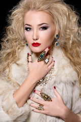 Beautiful blonde woman with curly hairstyle and bright makeup, perfect skin, cosmetology. Sexy vogue woman in fur and jewelry