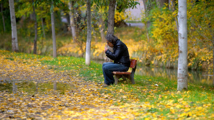 man smoking on a bench in autumn