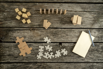 Blank notepad, pencil and piles of puzzle pieces, wooden blocks