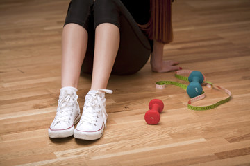 Naklejka premium Woman is sitting with fitness ball, weights and measure