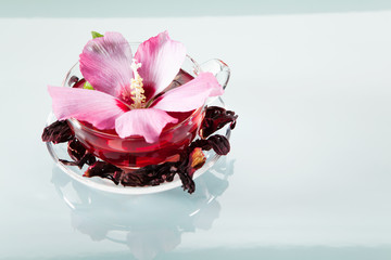 Malvenblütentee mit frischen und getrockneten Blüten in einer Glastasse
