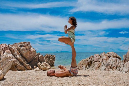 beautiful couple doing acro yoga on the beach