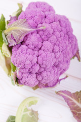 large purple cauliflower with a knife on a white wooden background, high-key, top and side views