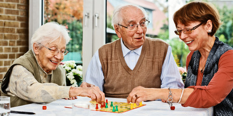 Elderly couple and daughter, playing board game - obrazy, fototapety, plakaty