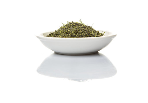 Dried green tea leaves over in white bowl bowl over white background