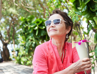 beautiful elderly woman in a hat with a cocktail in hand. Summer