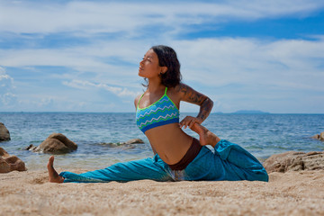 Fototapeta na wymiar beautiful young woman doing yoga on the beach