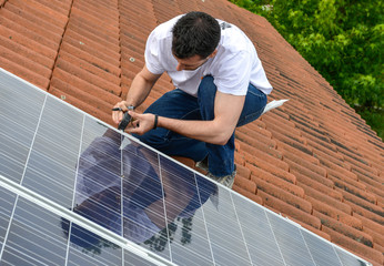 electrician on roof with curved tiles measuring for solar panel