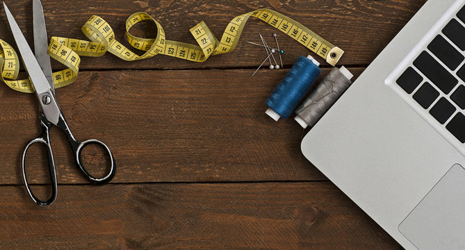 Photo of an old scissors, sewing set and computer on wooden table. High angle view panoramic photo