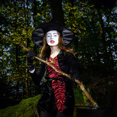 Naklejka premium Girl in the forest dressed Halloween witch costume