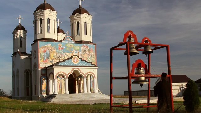 Christian monk ringing bells at the holy monastery of Codru in Dobrogea, Romania